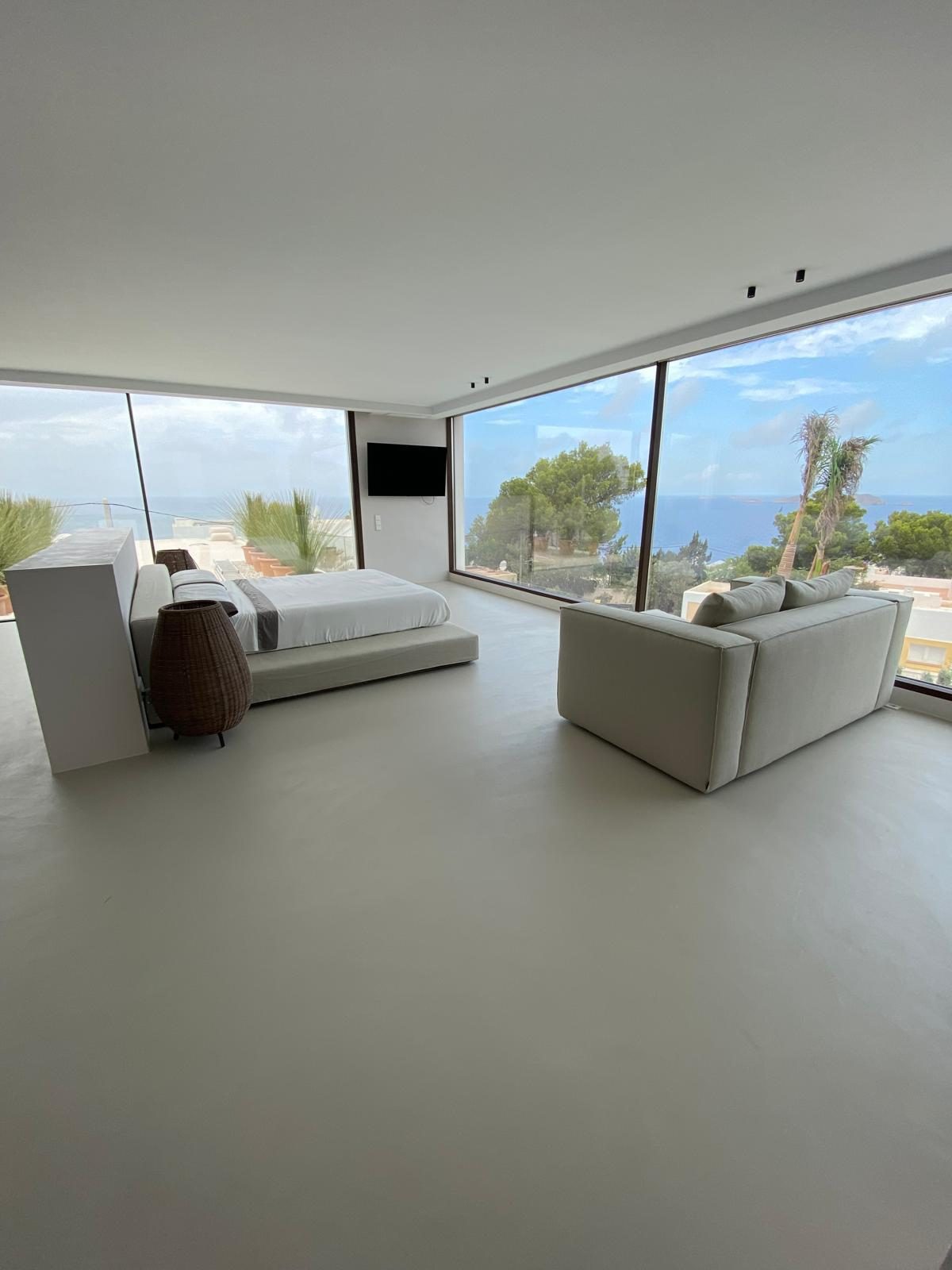 Dormitorio con suelo de microcemento PAVICEM y vistas al mar