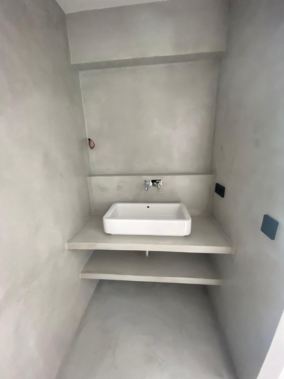 Baño con lavabo y estante de microcemento continuo