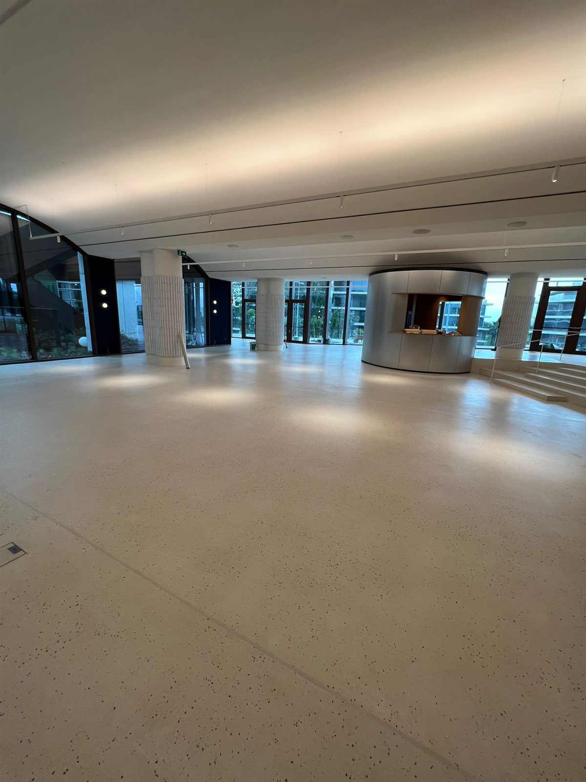 Gran sala diáfana con terrazo continuo Stone Feel y barra circular
