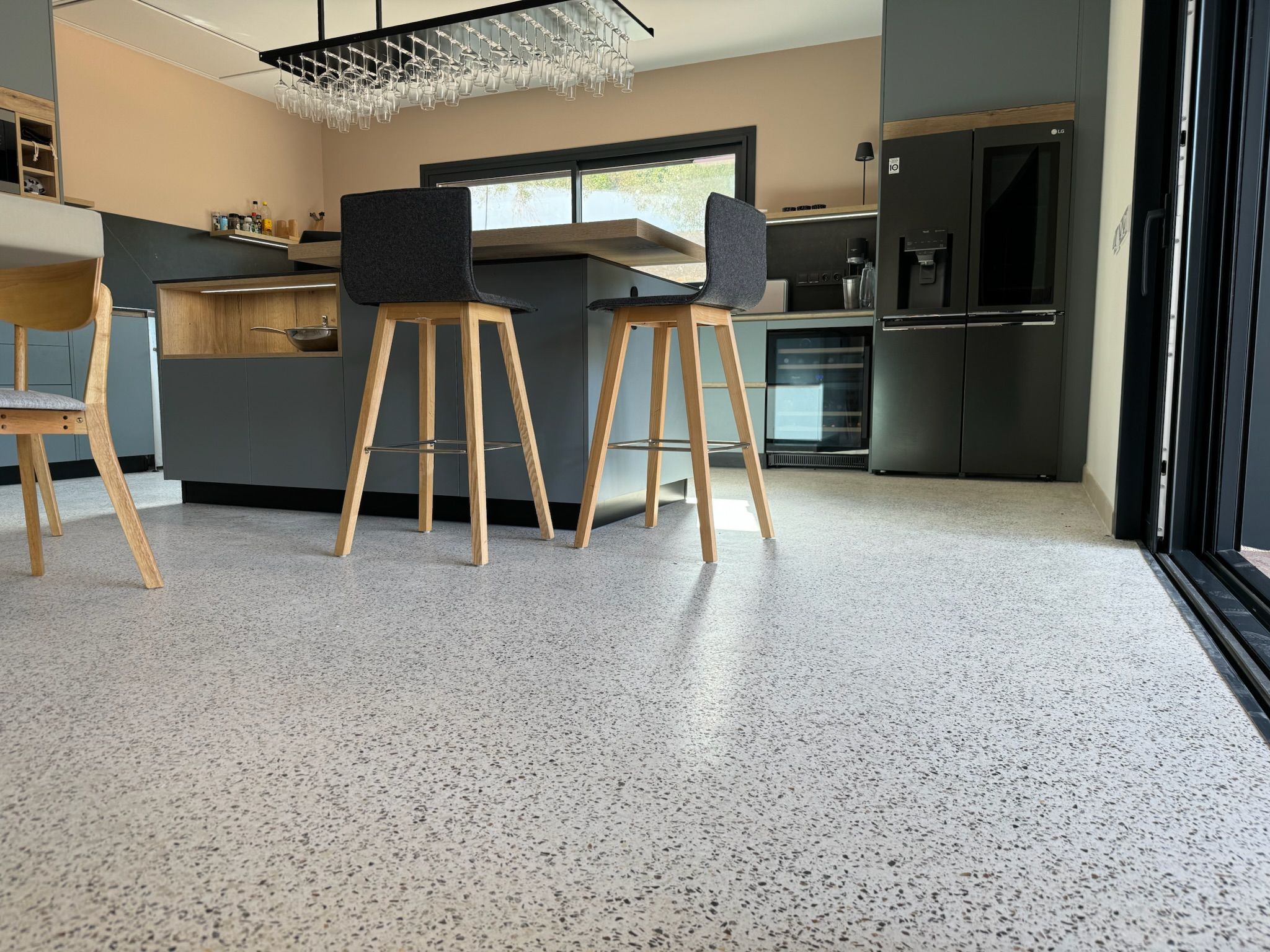 Cocina abierta con pavimento Stone Feel granulado y encimera de isla con taburetes
