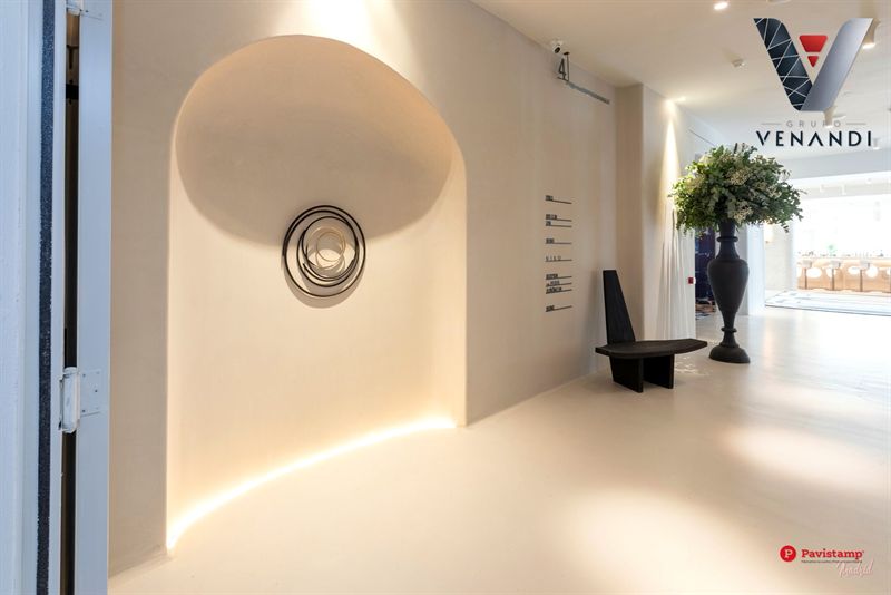 Pasillo de hotel con suelo Decopox claro y una hornacina curva iluminada
