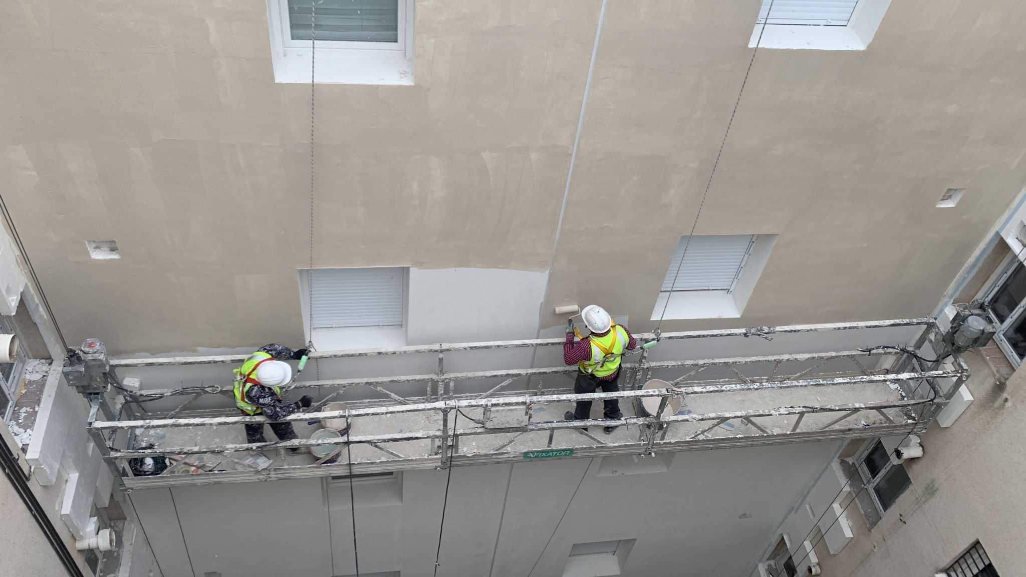 Operarios aplicando sistema SATE en góndola de trabajo en Casería Aguirre, Granada